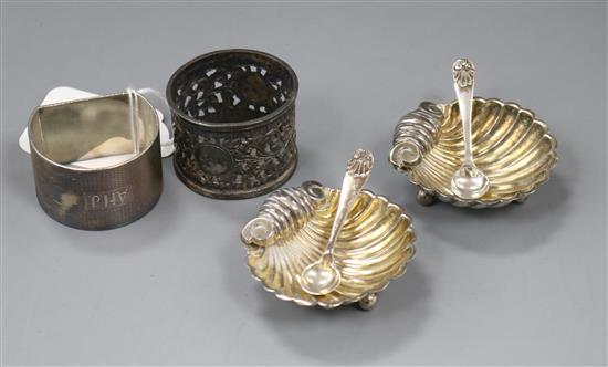 A pair of silver shell salts with two spoons and two napkin rings, one silver.